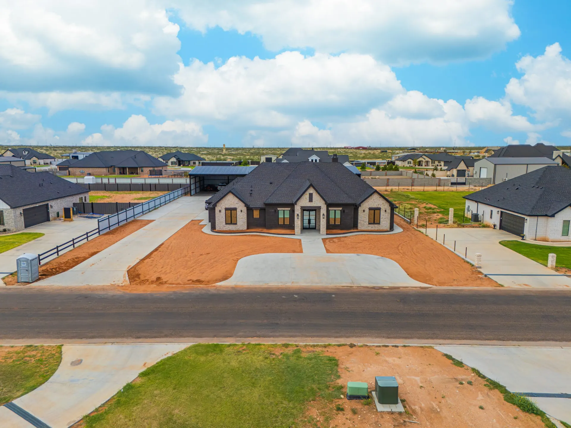 Aerial view of 1607 NW 12th St in Estates of Ezra — stone and stucco home with a curved drive and detached garage